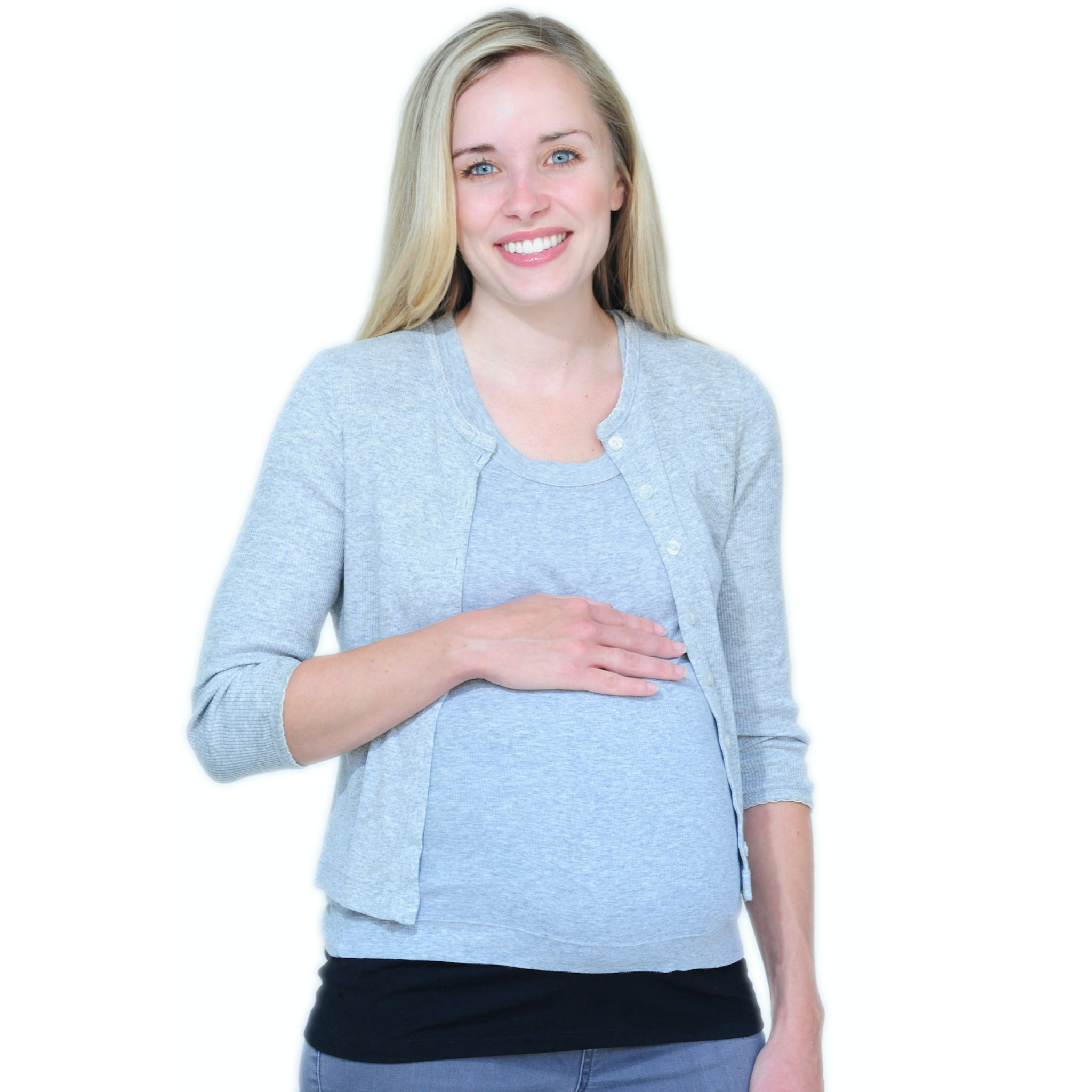 A smiling pregnant woman wearing a light grey top, over a black tummy band and blue jeans, standing against a solid white background.