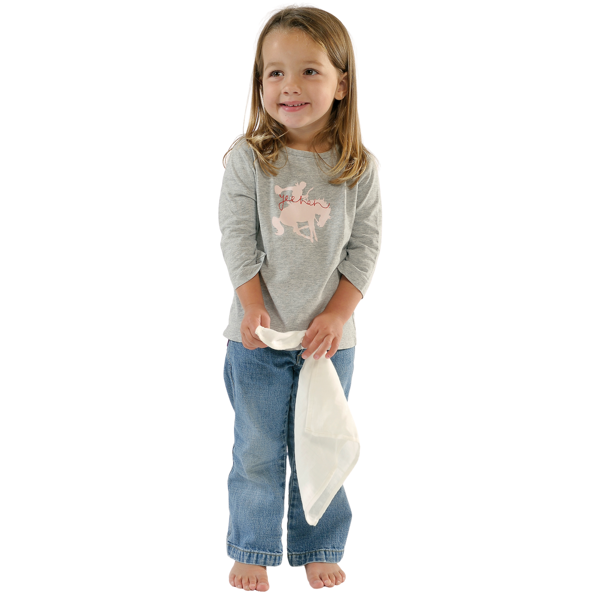 A young girl with long light brown hair stands barefoot against a white background, wearing a grey long-sleeve shirt and blue jeans, holding an inspired mother cuddle blanket