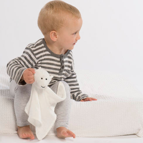 Baby in pajamas holding a white my luvvie monkey comforter 