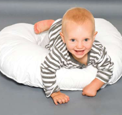 Baby lying on a white maternity support pillow enjoying supervised tummy time