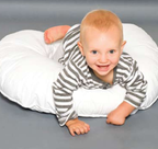 Baby lying on a white maternity support pillow enjoying supervised tummy time